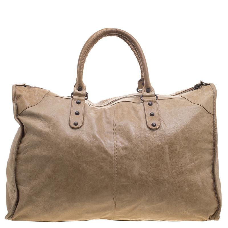 Add a stylish number to your closet with this oatmeal leather tote from Balenciaga! The beige beauty is an excellent play of leather trims, accented with black tone hardware and dual rolled handles. The soft fabric interior houses a small zipper to