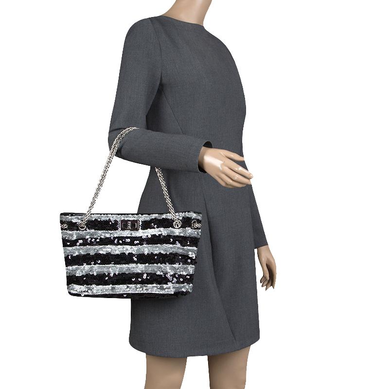 Charm your way through every gathering by swinging this Reissue bag from Chanel. Crafted from black/silver sequins in a stripe pattern, it comes with a turn lock closure that opens to a spacious satin lined interior that will easily hold all your