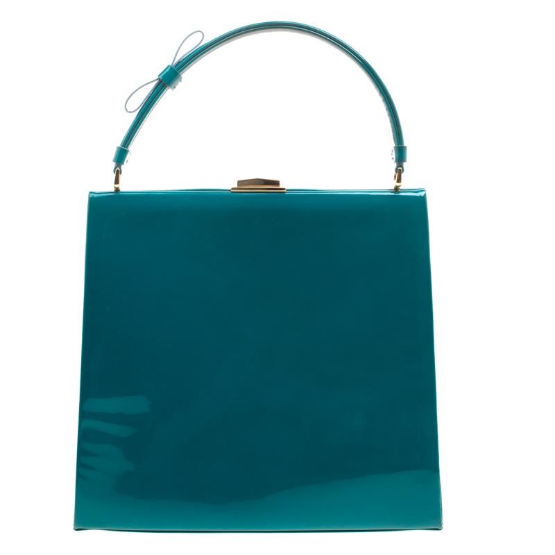 This top handle bag from Valentino is crafted from green patent leather. The bag features a cute bow on the top handle, a lock closure and protective metal feet at the bottom. It comes with a well sized satin lined interior that houses a slip and