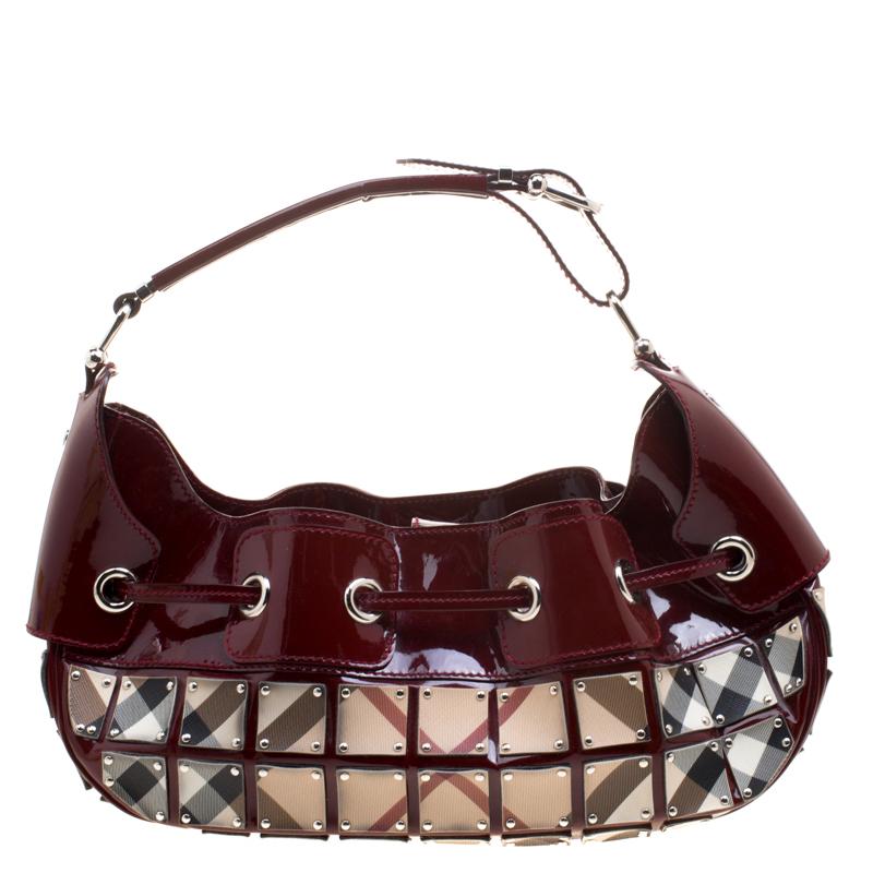 This Burberry Warrior hobo will make a standout addition to your collection. Its patent leather exterior is coupled with a classy burgundy colour that has square panels with the signature Burberry check pattern. Its nylon lined interior has enough