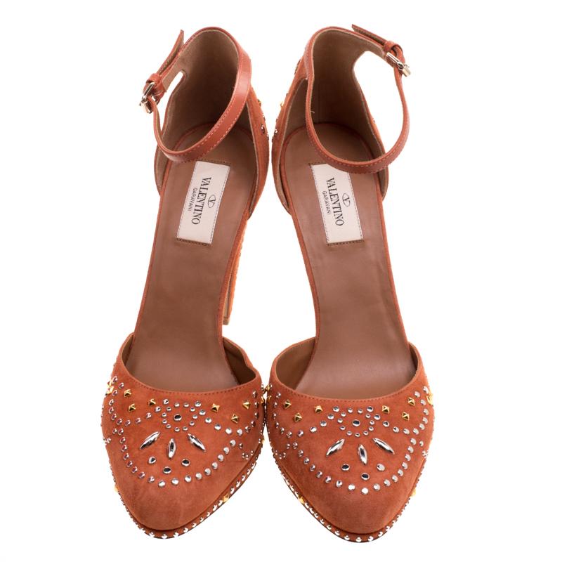 Walk and feel like a diva with these platform pumps from Valentino. They've been decorated with beautiful crystals all over its orange suede exterior and designed with closed toes on platforms and a closed back with leather ankle straps. The pumps