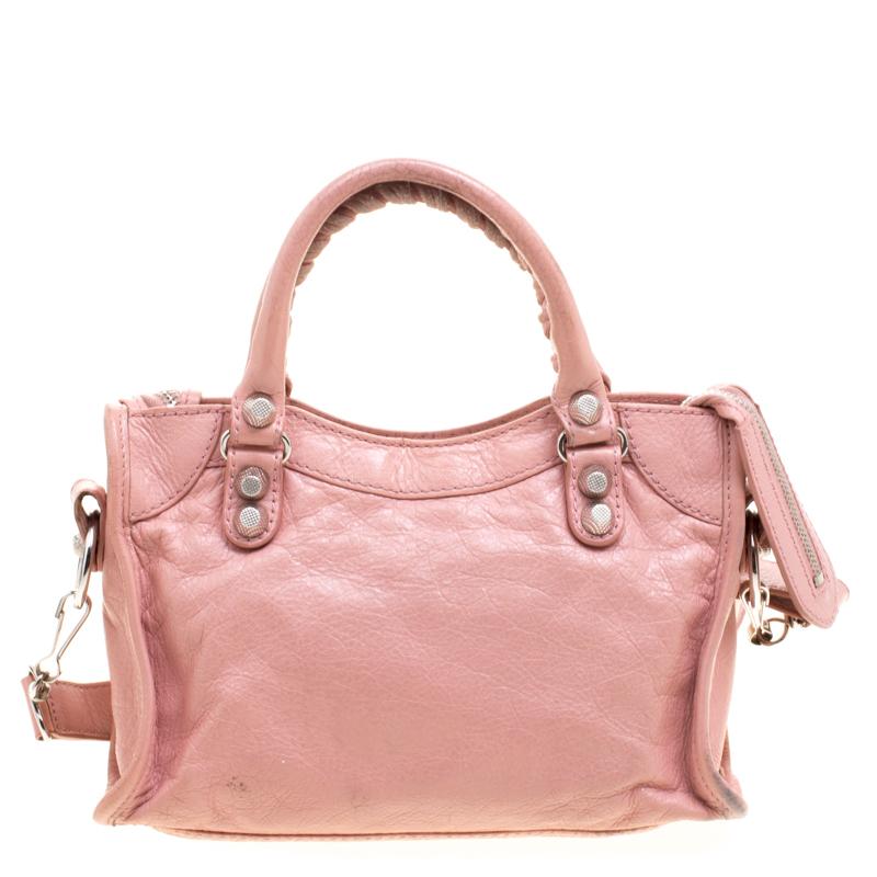 This City bag from Balenciaga is perfect for your everyday agendas. Crafted from pink leather, this bag is unique in its silhouette and features an interplay of large silver tone studs and buckle detailing. The bag has dual rolled top handles, a