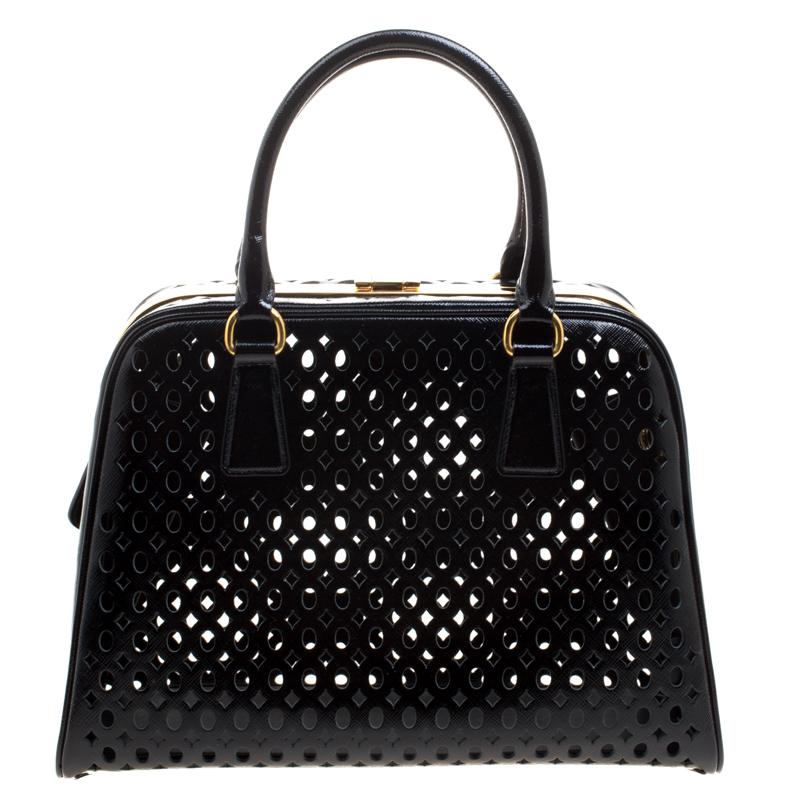 Designed in a stunning black perforated Saffiano patent leather, this Pyramid tote features a sturdy structure and fitted with two rolled top handles. Detailed with gold-tone accents and a snap top closure, this bag can easily hold all your evening