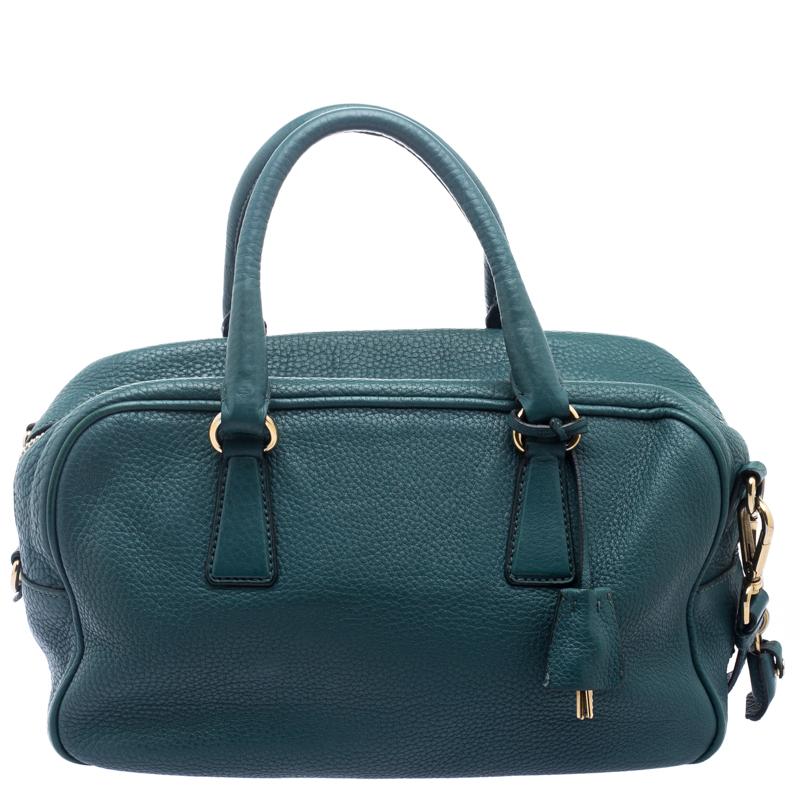 This Boston bag by Prada is crafted from leather and styled in a teal green shade. It features two top handles, a shoulder strap, and a spacious nylon interior to house your essentials. This bag works well for all occasions.

Includes: Original