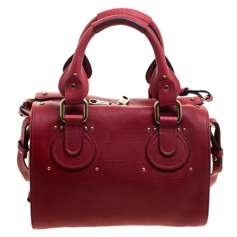 A red bag like this simply brings out the best of any outfit. This petite Aurore satchel from the house of Chlor features a gorgeous red leather body and detailed with gold-tone studs and tonal stitching. It comes with two rolled top handles and a