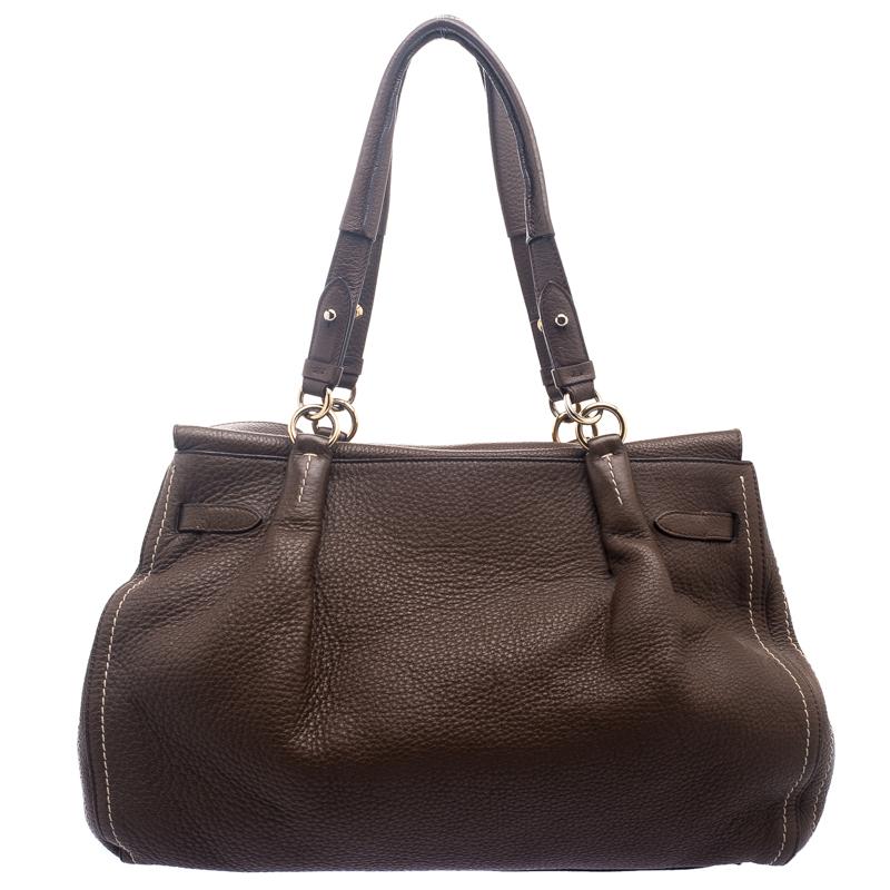 Featuring a chic and fabulous style, this Salvatore Ferragamo satchel is a joy to own. Crafted from leather in a stunning brown, it features dual handles and protective metal feet at the bottom. It opens to a spacious suede lined interior that