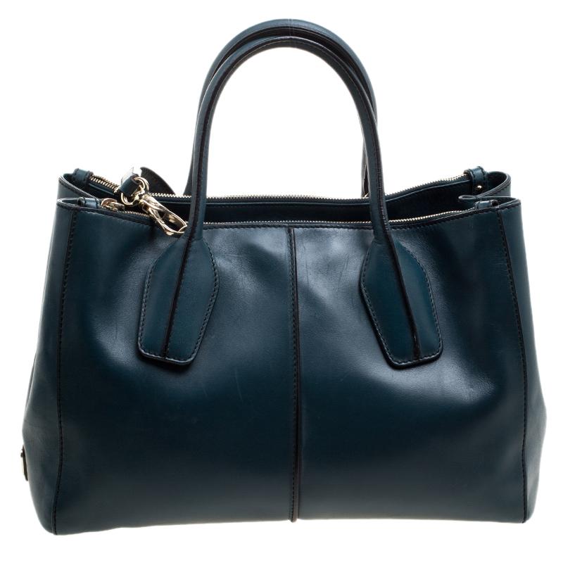 Bold and impressive, this TOd's Shoppers tote is crafted in a luxurious blue-green leather body and topped with two rolled top handles. It comes with a main compartment housed between two zipper compartments on either side. It also features a