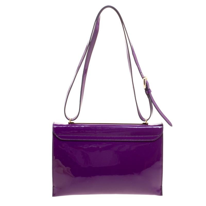 This Salvatore Ferragamo shoulder bag is designed in a sleek, square silhouette in a gorgeous purple patent leather. It features a flap style secured with a gold-tone lock closure. Use it as a shoulder bag or a sling bag by adjusting the flat strap.