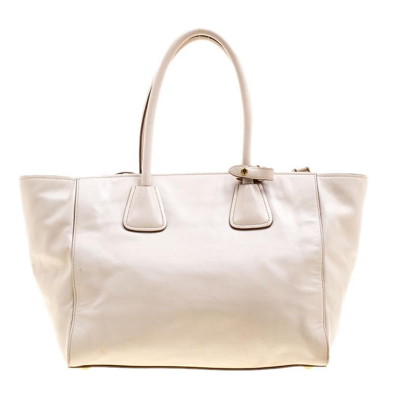 A sleek bag from Prada will never fail to impress you, and this Phenix tote bag is a must for every luxury lover. Crafted in off white vitello leather, this bag features a gold tone zippered pocket at the front along with the signature logo design.