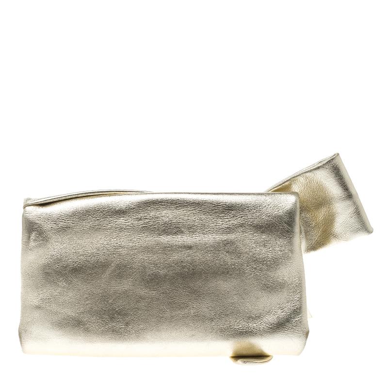 This small and beautiful Valentino clutch is perfect to add a moment of glam and shine to your special outfits with minimal effort. Crafted in metallic gold leather, this clutch features a huge bow detail on the front flap which opens to a beige