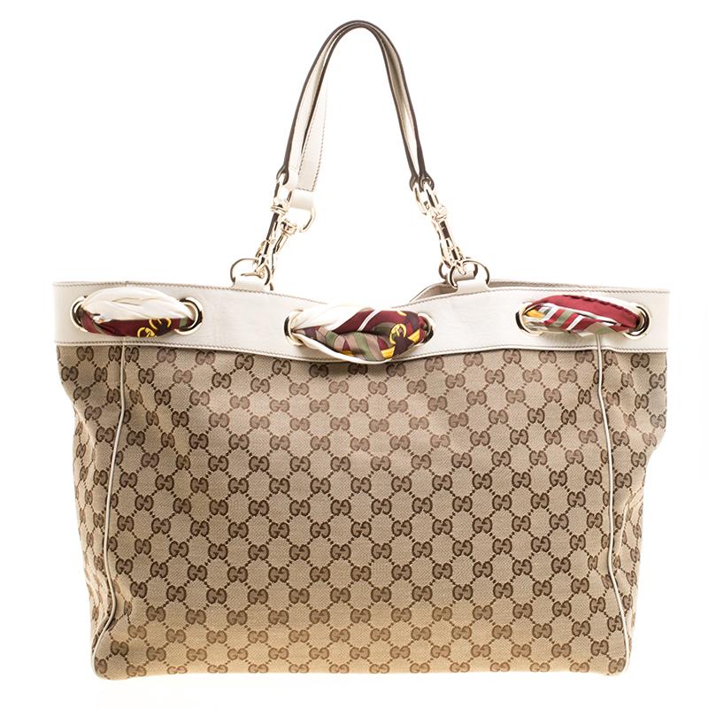 Take your style a notch higher with this Positano tote from Gucci. Cut out of GG canvas, the bag features two handles, a spacious fabric interior and a scarf laced around the top. The tote is complete with gold-tone hardware and it is truly a
