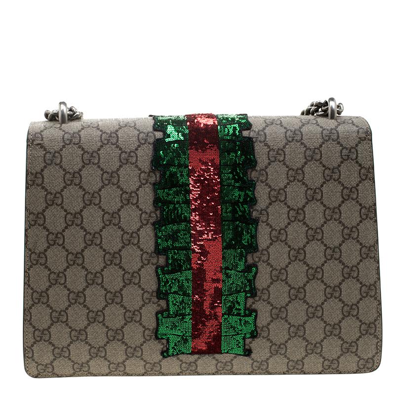 This exquisite Gucci shoulder bag is crafted from traditional Gucci GG monogram supreme canvas. It has embroidered appliqués illustrating four pink crystal-encrusted lightening bolts and red crystal encrusted lips. The front flap is complimented