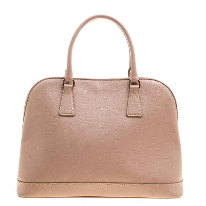 This stunning Promenade satchel is high on appeal and style. Dazzling in a classy beige hue, the bag is crafted from Saffiano leather and features two rolled handles and a shoulder strap. The snap button leads way to a nylon-lined interior with