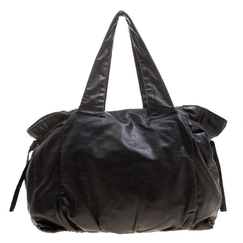 This Hysteria tote from Gucci is built for your everyday use. Crafted from Guccissima leather, it has a black shade with ties on the sides and two handles for you to easily parade it. The fabric insides are spacious and the tote is complete with the