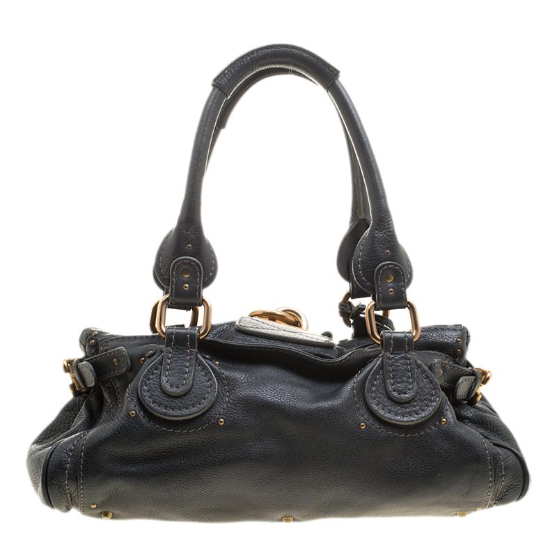 Chole’s Paddington satchel is glamorous indeed with a retro vibe. The chunky lock on the front and the dangling chord with the key, grab all the attention. Crafted from black leather, its fabric interior is quite roomy and can house all your