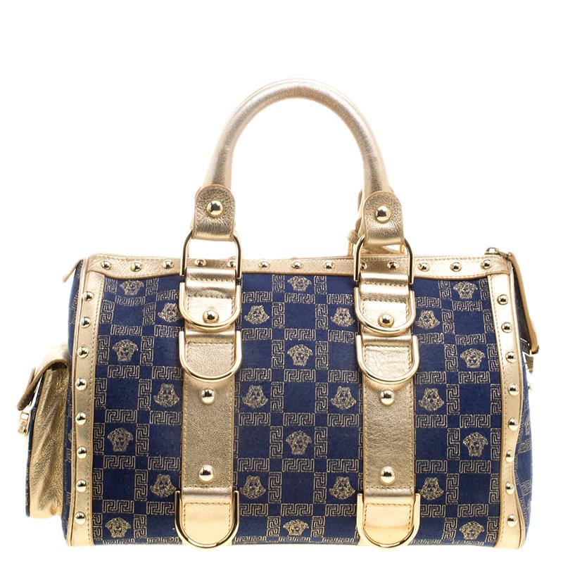 How gorgeous is this satchel from Versace! It carries an outstanding design and a fabulous interplay of blue fabric and gold leather. It has a top leading to a fabric interior while being held by two top handles. The signature prints and the brand