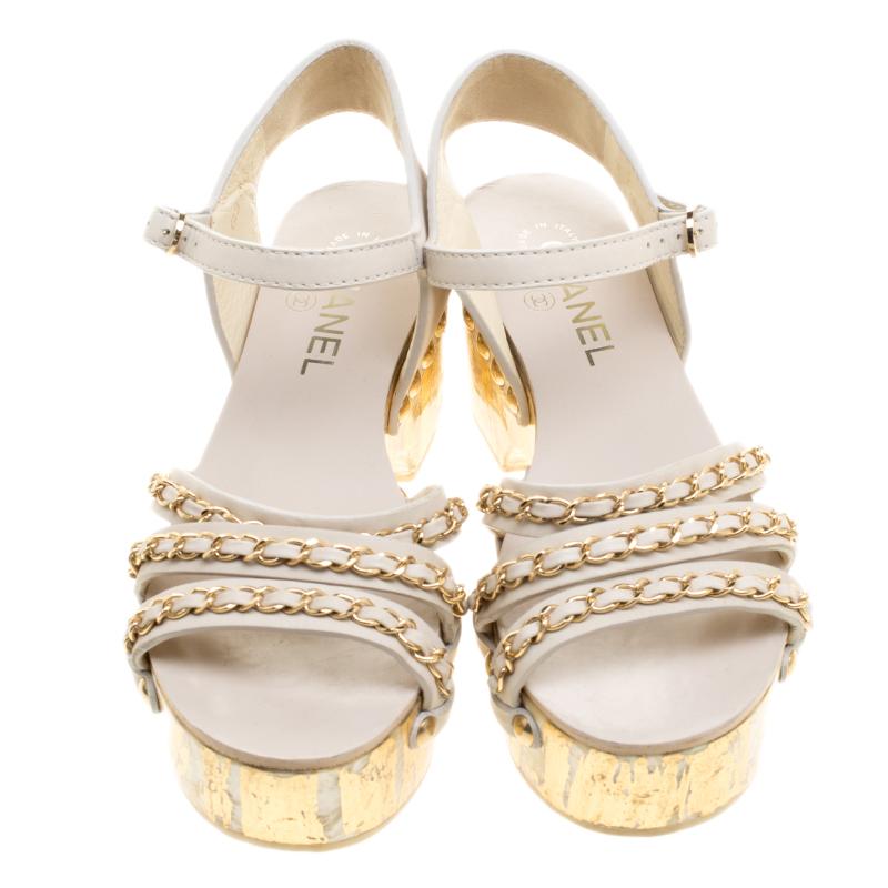 Add some bling and shine to your summer wear and day time wear collection with these Chanel ankle strap platform sandals. Constructed in ivory leather, these sandals feature a strappy front with gold tone chain detail all over for added style. With