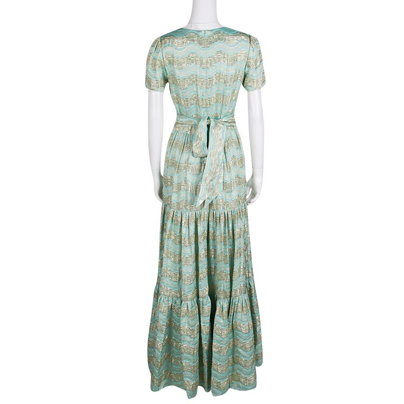 This Temperley London gown is brimming with elegant details that have been carefully incorporated to create a flattering piece. The tiered, flouncy bottom, wavy lurex patterns, and the notable tie detail at the rear make this Verve gown a