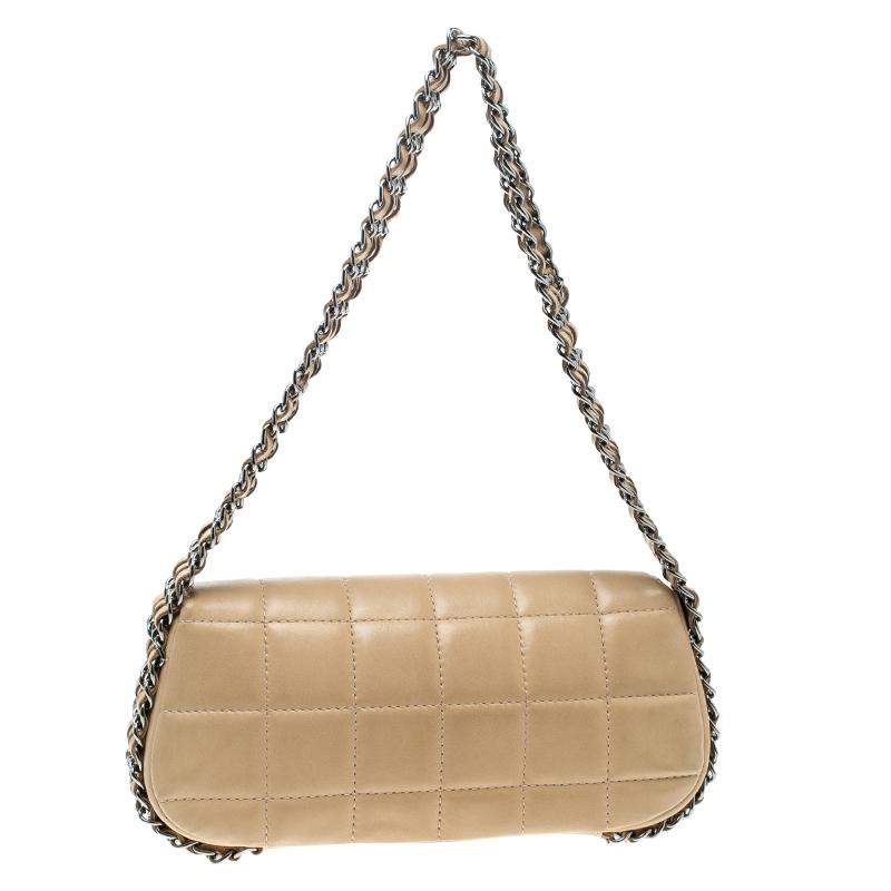 This beige bag from Chanel is the ideal fashion adornment for everyday use or special events. The fabric interior is tough and well-sized while the leather exterior is covered in their chocolate bar pattern. Complete with the CC on the flap and