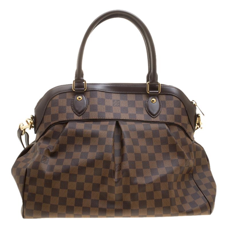 This Trevi GM bag by Louis Vuitton has been crafted from Damier Ebene canvas. It features dual leather handles, a removable shoulder strap, gold-tone hardware and protective metal feet at the bottom. The top zip closure opens up to a spacious