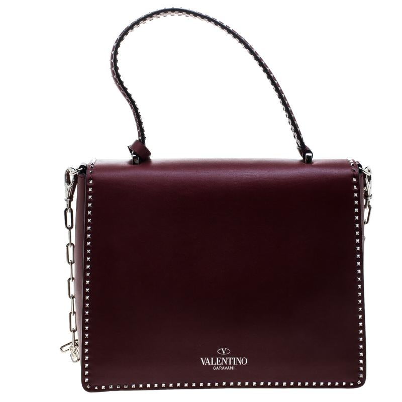 Catch admiring glances when you carry this Micro Rockstud handle bag from Valentino! Crafted from burgundy leather, the bag has a single top handle and detachable chain-link shoulder strap. The bag features the iconic Valentino Rockstuds outlining