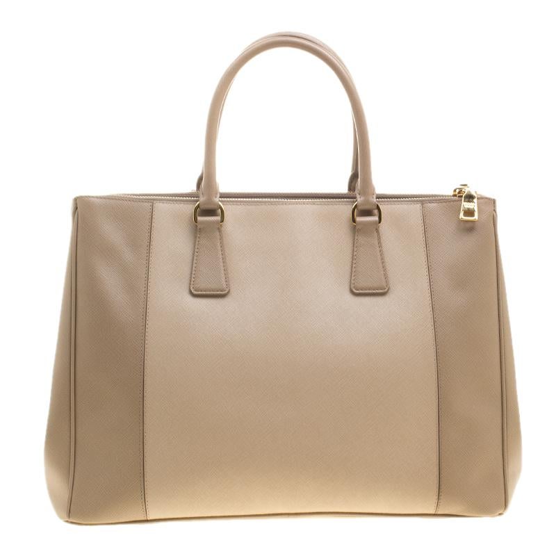 Handbags can transform any outfit, just like this classy tote from the house of Prada can. Crafted from Saffiano leather and lined with nylon on the insides, it features dual rolled handles, protective metal feet and the brand plate flaunted on the