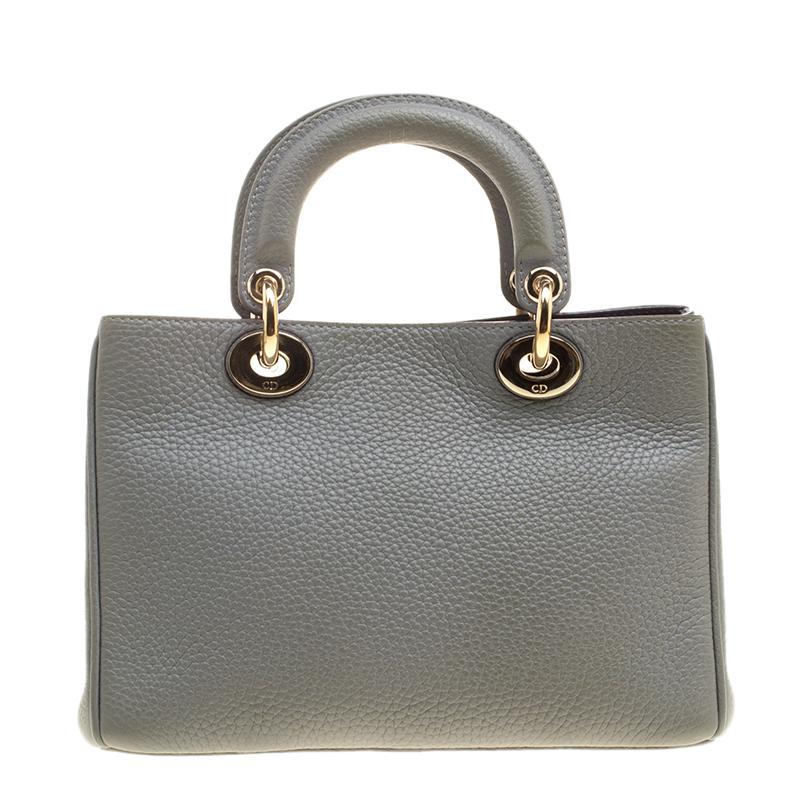 The Diorissimo bag from Dior is a piece that has never gone out of style. The pebbled leather bag comes in a classy grey shade with silver-tone hardware and Dior letter charms. It features two top handles and a leather interior with slip pockets and