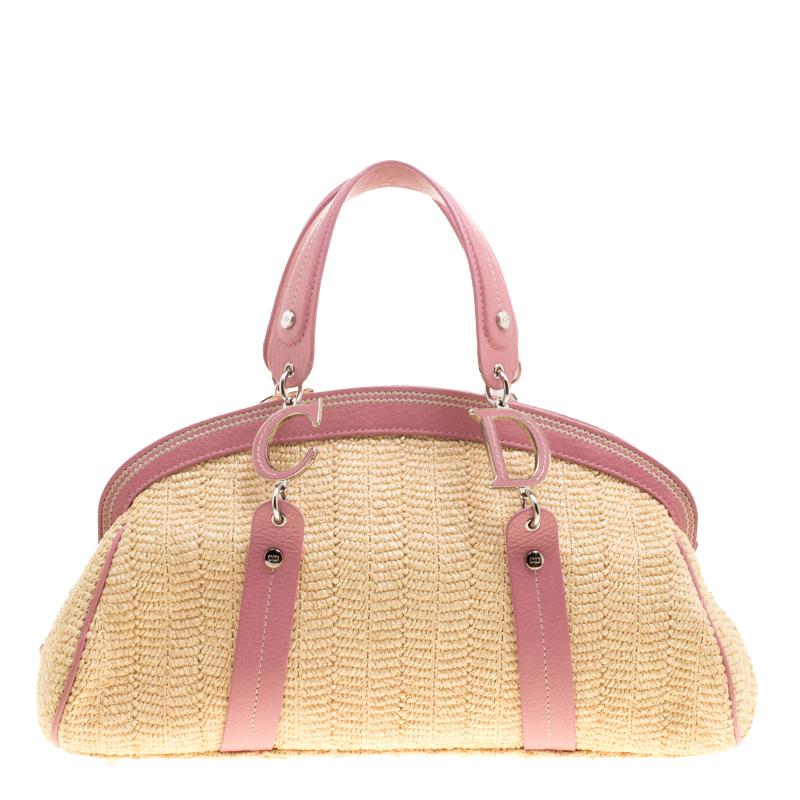 This detective satchel from Dior is a stylish way of carrying your essentials. It has a beautiful exterior adorned with straw and flower accents along with feminine pink leather trims. It is equipped with two top handles that are beautified with