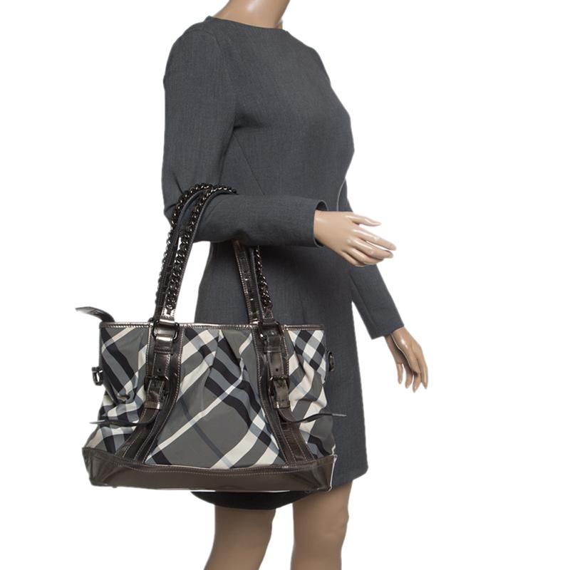 This Burberry Medium Lowry tote will get you through all your daily errands, complementing almost all styles and ensemble. The exterior of the tote is crafted from signature check patterned nylon with leather trim that features stylish buckle
