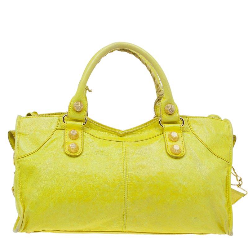 This splendid Balenciaga Giant 21 City Bag is practical and stylish. Made from fine lambskin leather in a bright yellow color, it features a front zipper pocket, stud and buckle motifs, protective feet and gold-tone hardware. It is finished with