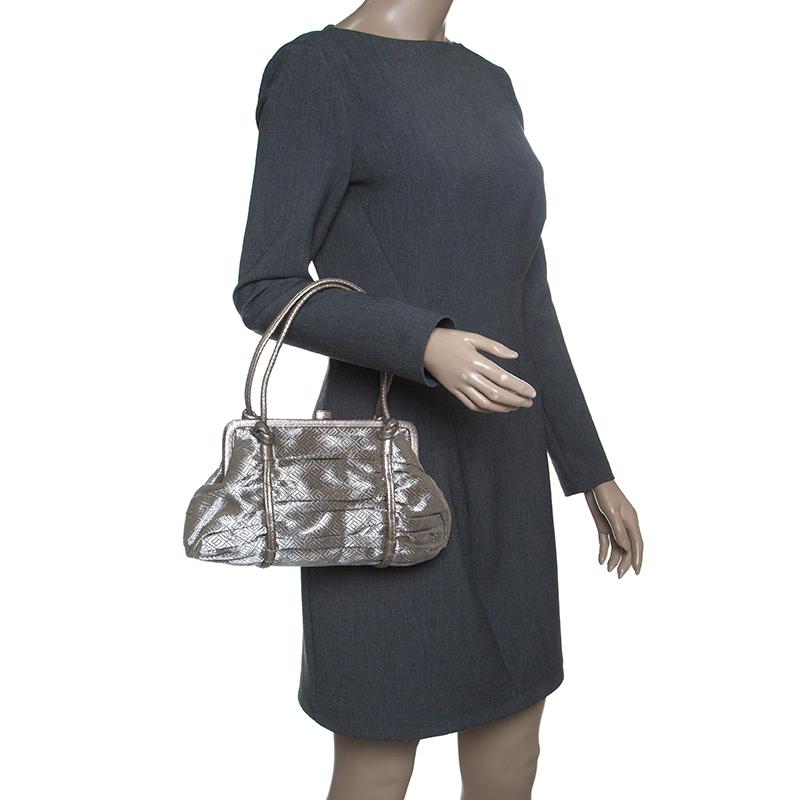 Made of silver fabric with bronze trims, this satchel makes an ideal addition to your wardrobe. Keep the attention on this Bottega Veneta bag by pairing it with statement pants and nude pumps. The suede interior makes it a useful accessory. The