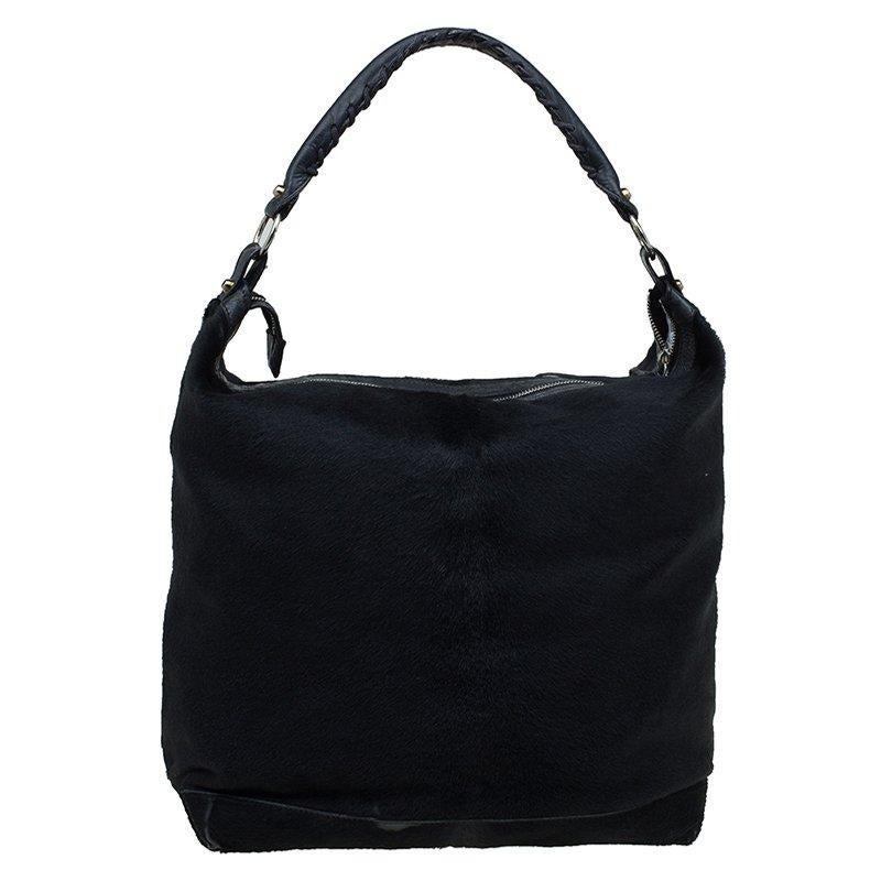 Constructed from black calf hair leather and decorated with giant silver-tone hardware, this hobo bag from Balenciaga is perfect for the fitness freaks and for those who would never run out of comfort and functionality. Elegantly designed in slouchy