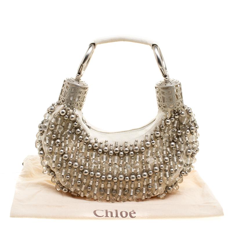 This Chloe design has an off-white canvas exterior with bead embellishments and silver-tone hardware. The hobo carries a crescent shape and features a top-zip closure that opens to a fabric-lined interior with the brand's label. Raise your glamour