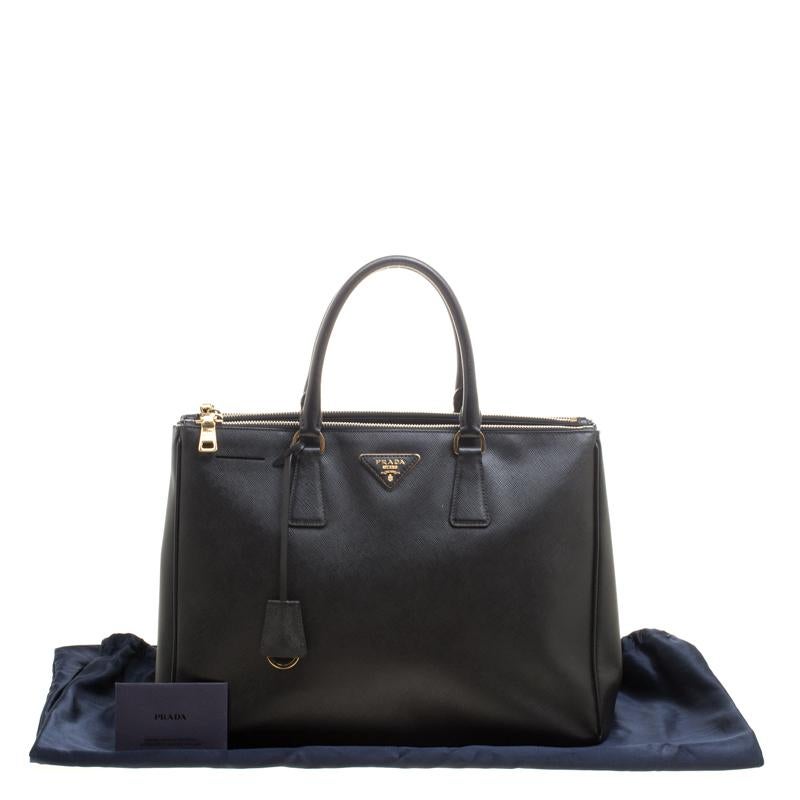 Beautifully crafted from Saffiano Lux leather, this Prada tote is a creation you can't miss. It has a classy black exterior along with two zippers and a spacious nylon interior that will hold your necessities. The bag is held by two handles and is