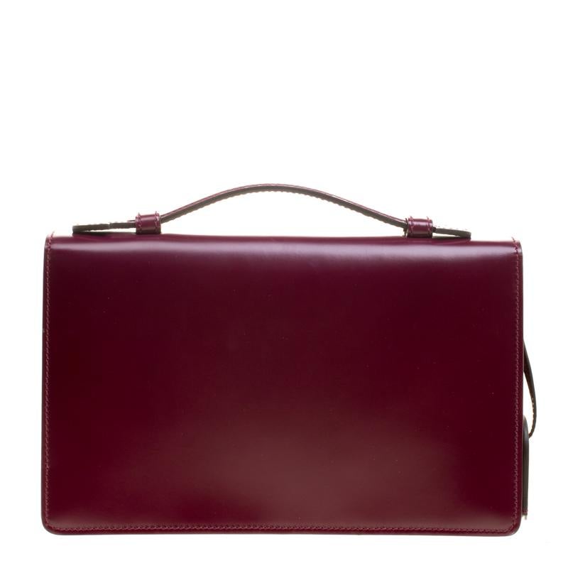 Create a winning look with this Briefcase clutch by Gucci that comes in a striking style and excellent craftsmanship! Crafted from leather it has a stunning purple exterior that flaunts the lady lock in silver tone. The suede lined interior has two