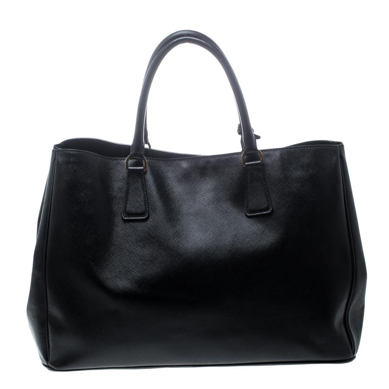 High in appeal and style, this Gardener's tote is a Prada creation. It has been crafted from Saffiano leather and shaped to exude class and luxury. The black bag comes with two handles, a spacious nylon interior, a key ring, and gold-tone hardware.