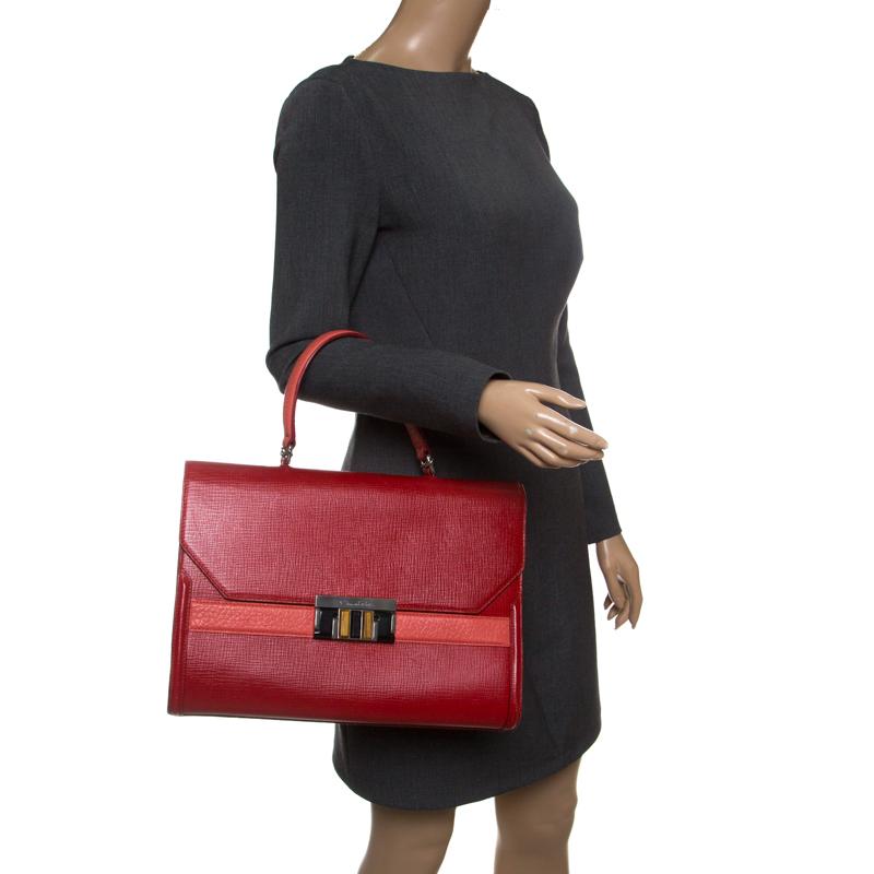 Hints of class and luxury define this Oscar de la Renta bag. Designed in a structured silhouette, this bag is crafted in rich red leather and arrives with a classic top handle that will tote effortlessly over your arms. The sizeable piece will
