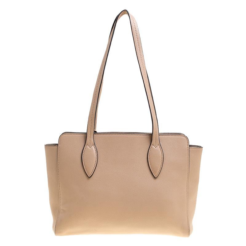 This lovely bag from Prada will put you in the spotlight. This light brown bag is crafted from leather and features a chic silhouette. It flaunts dual shoulders straps, an attached concealed ring accent and the brand's logo shimmering in gold. Its