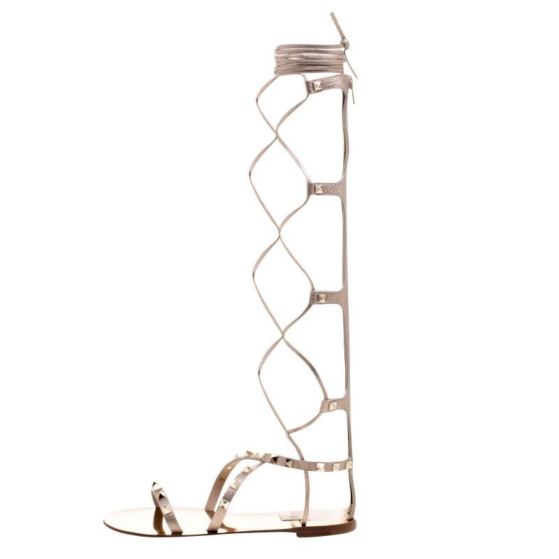 These amazing knee-high gladiator sandals from Valentino's Rockstud collection are fabulously evergreen. Set in metallic bronze leather, these sandals feature an open toe silhouette and crisscross straps with back zippers. They flaunt the brand's