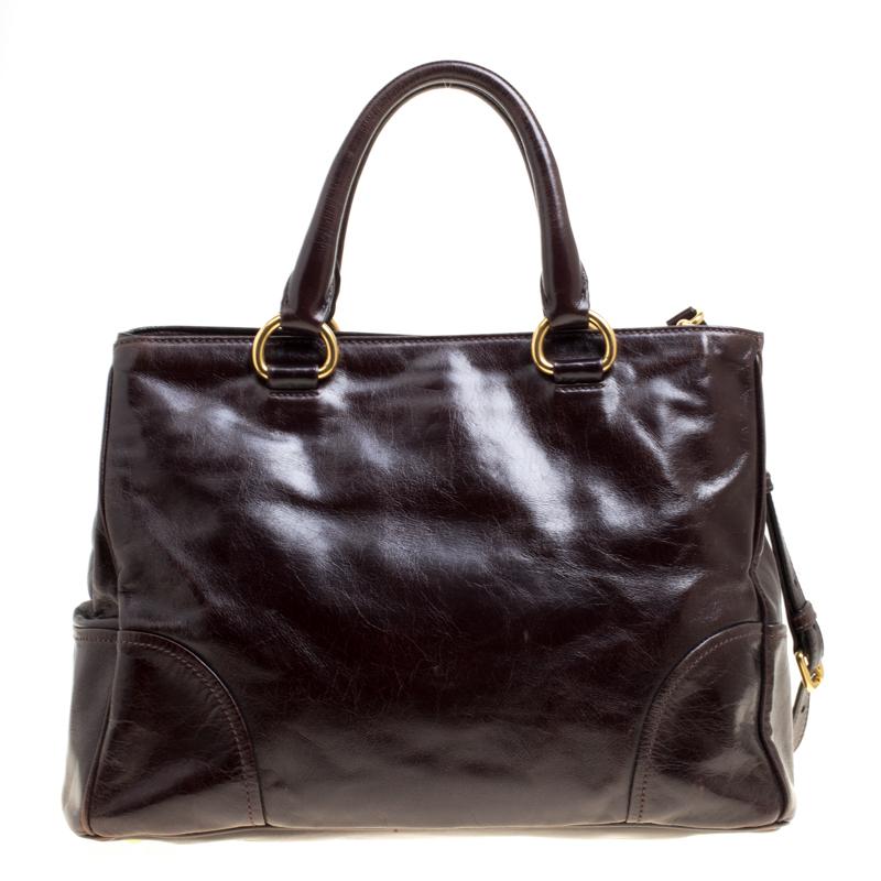 This Prada creation is a handbag that brings joy to one's sight! It has been beautifully crafted from brown leather and designed with a spacious nylon interior and the brand logo on the front, whilst being held by two top handles and a shoulder