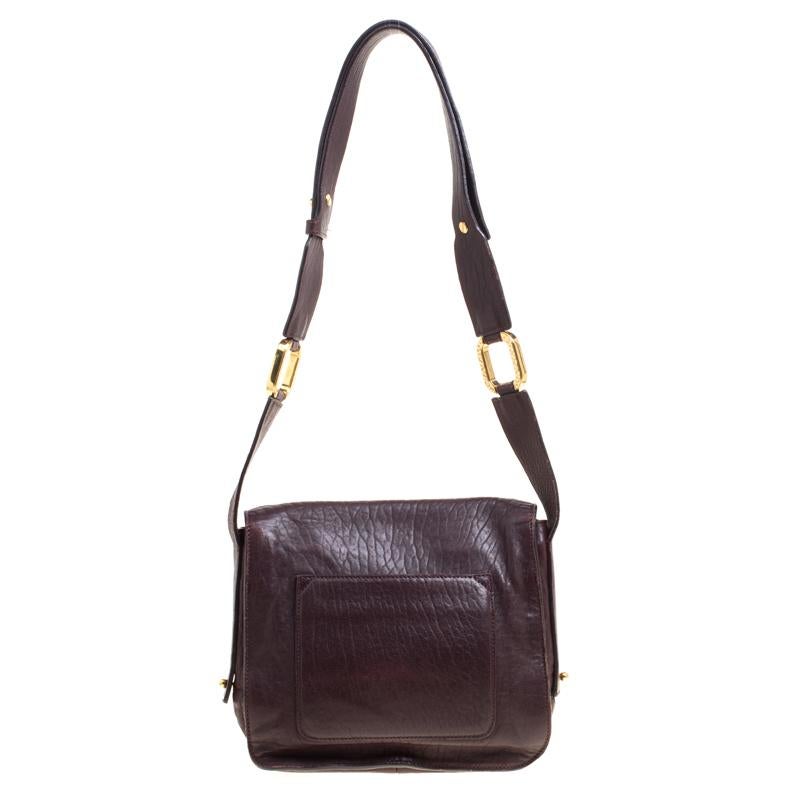 Masterfully made in leather, this dark burgundy crossbody bag can, with no trouble, hold more than just essentials. The interior is lined with canvas and is held by a shoulder strap. This exquisite piece, featuring a gold-tone lock on the front