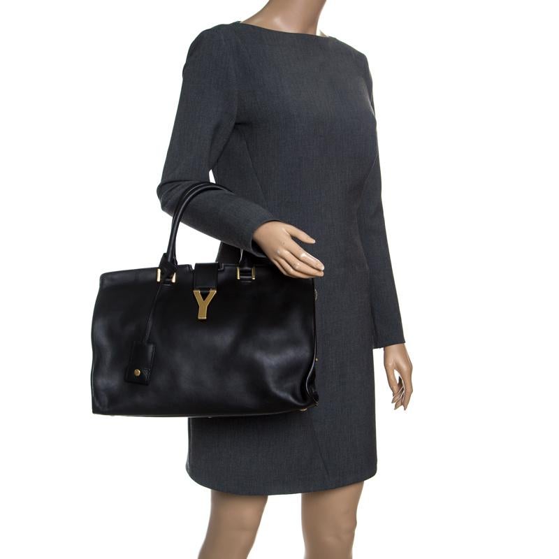 This elegant black Cabas Chyc tote from Saint Laurent is ideal for everyday use. Crafted from leather, the bag is detailed with a gold-tone Y motif, dual rolled handles and metal feet. The top zip closure opens to a spacious suede interior that is