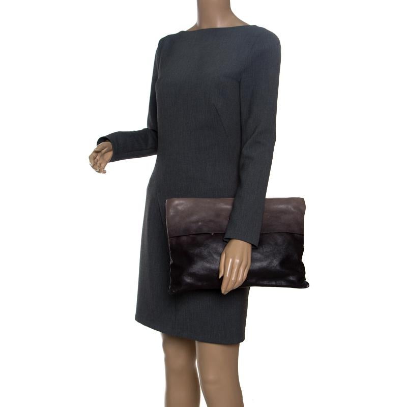 Prada yet again amazes us with this lovely Folders clutch that looks very sophisticated and stylish. The black and grey ombre clutch is crafted from leather and features a glace texture. It flaunts a front flap closure with the brand logo on it and