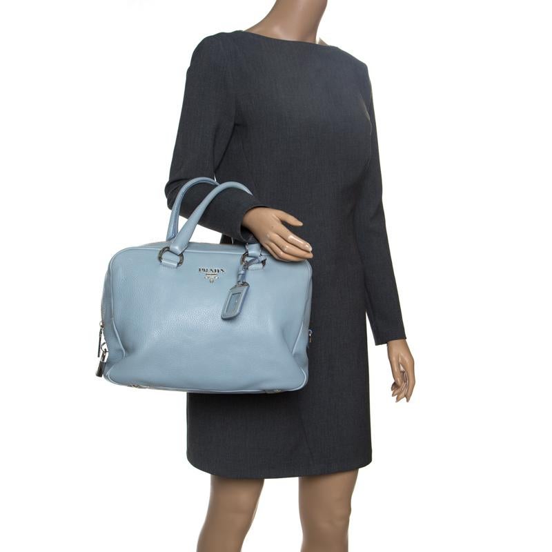 This Prada Bowler bag will be a gem of an addition to your collection. Crafted in Vitello Diano leather in beautiful light blue colour, this structured bag features the signature Prada emblem at the front, rolled top handles, and a name tag. It also