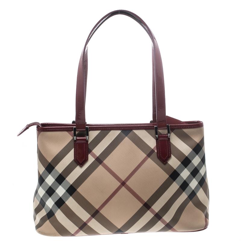Burberry's Nickie tote is chic and smart. Crafted from classic Nova Check PVC and styled with patent leather trims, it features two handles and protective metal feet at the bottom. The zip closure opens to a fabric lined interior that has enough