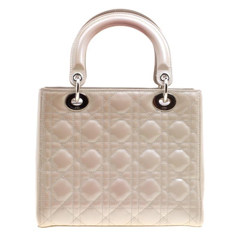 This sophisticated and feminine Lady Dior tote in your hand is apt for the perfect Dior look. Crafted from patent leather, this grey tote is accented with quilted pattern and silver-tone hardware. It features signature Dior charms, two round