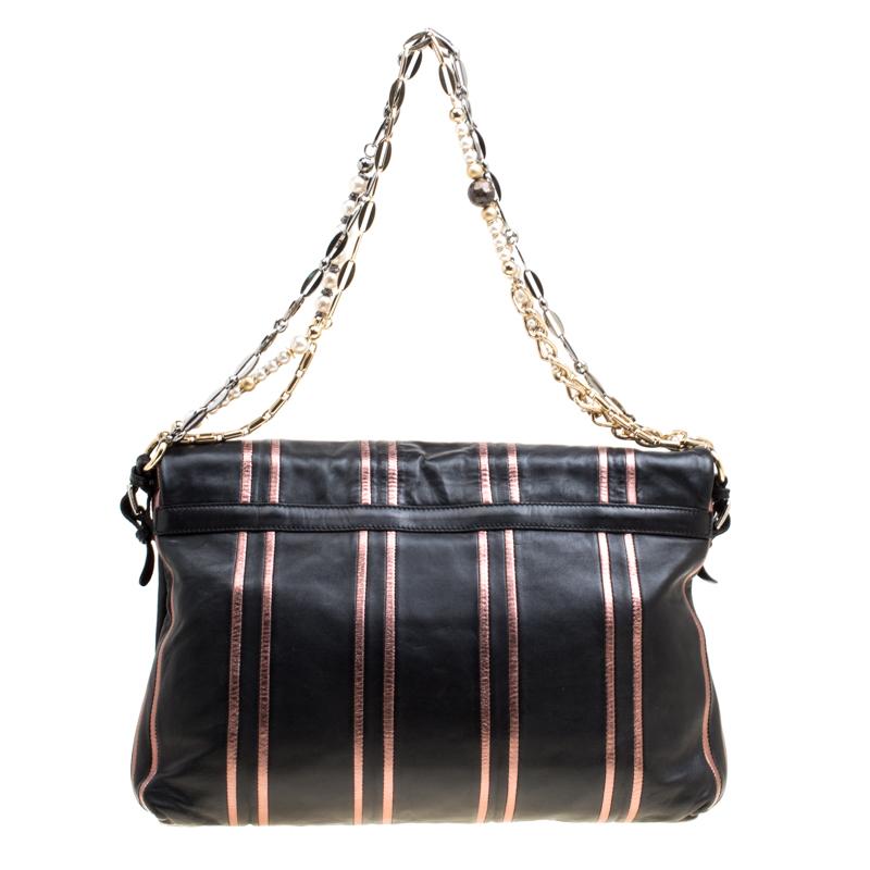 This shoulder bag by Dolce and Gabbana is a lovely handbag to own. The exterior is made from black leather with pink stripes. It is finished with a front Dolce and Gabbana plaque and showcases a chain link strap that is ornamented with pearls and
