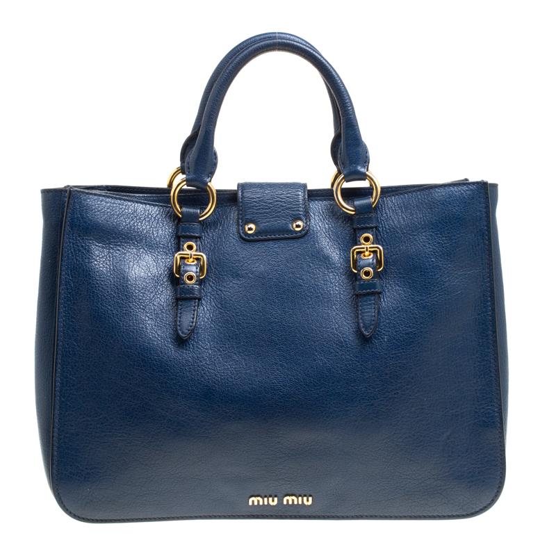 This Madras Executive tote by Miu Miu combines luxury and utility. It is crafted from blue leather with a front Miu Miu push-lock closure, rolled leather handles, a detachable and adjustable shoulder strap and gold-tone hardware. The interior is