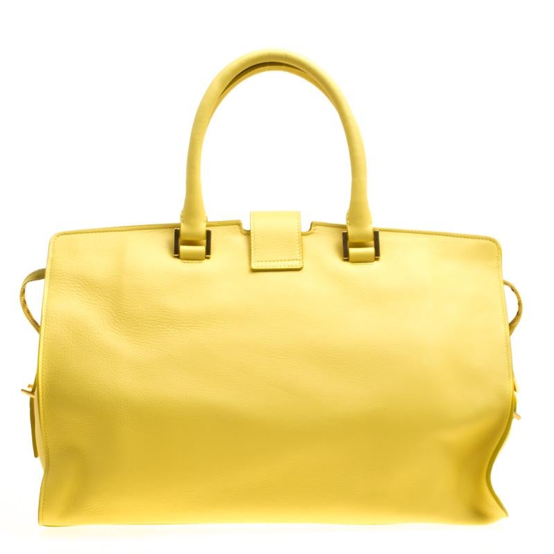 This elegant yellow Cabas Chyc tote bag from Saint Laurent Paris is ideal for everyday use. Crafted from leather, the bag is detailed with a gold-tone Y motif snap closure, dual rolled handles and protective metal feet at the bottom. The top zip