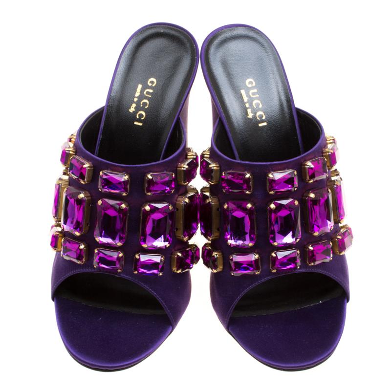 Shining with beautiful crystal embellishments on the uppers, these easily slip-on mules from Gucci are both pretty and feminine. They are crafted with the purple satin and have open toes and 11 cm high block heels along with strong, leather soles.